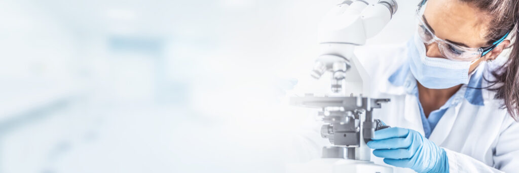 Forscherin mit Handschuhen arbeitet am Mikroskop in einem Labor. Content-Strategie für Medizintechnik-Unternehmen beim Textquartier Marius von der Forst.