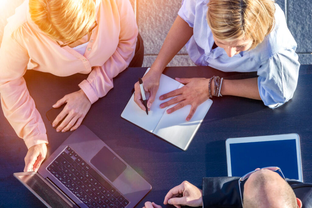 Team bei der Planung und Analyse von Inhalten mit Laptop und Notizbuch. Content-Strategie für Medizintechnik-Unternehmen beim Textquartier Marius von der Forst.