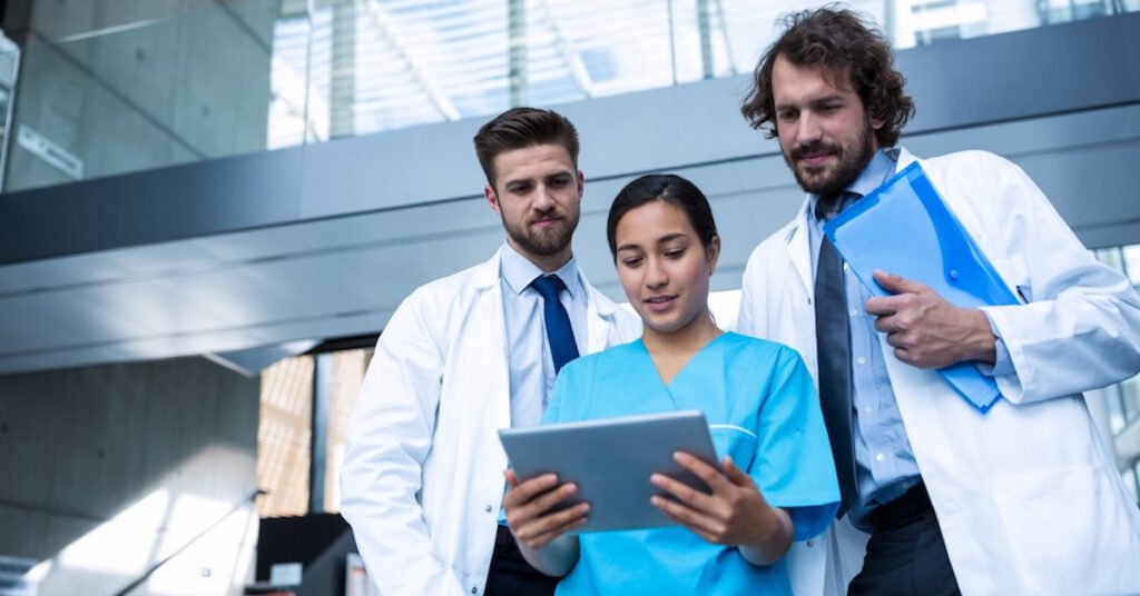 Drei medizinische Fachkräfte betrachten gemeinsam ein Tablet. Inhalte zur E‑E‑A‑T im Gesundheitswesen. Blogartikel beim Textquartier Marius von der Forst.