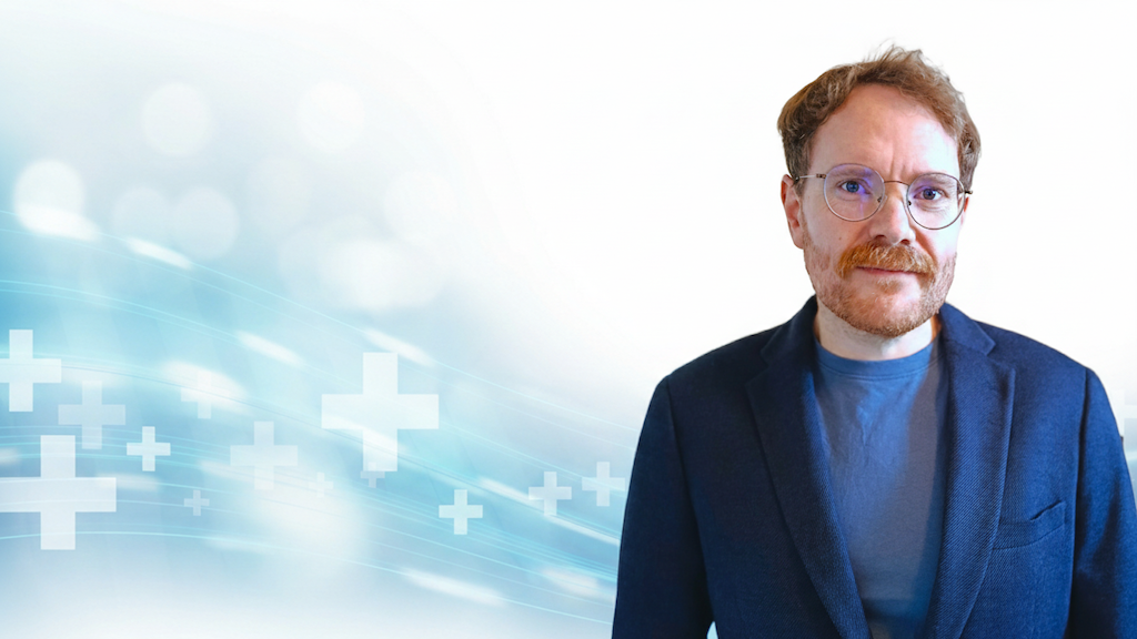 Marius von der Forst, Experte für Healthcare-Content-Strategie und Inhaber vom Textquartier. Professionelles Porträt vor medizinisch inspiriertem Hintergrund.