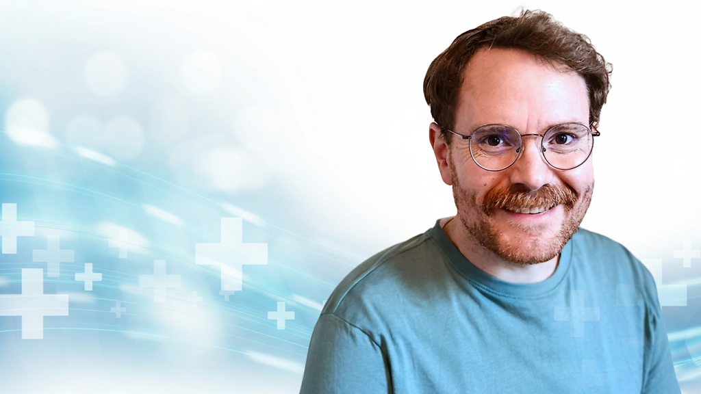 Marius von der Forst, langjähriger Texter, Content-Experte und Journalist sowie Inhaber vom Textquartier. Professionelles Porträt vor medizinischem Hintergrund.