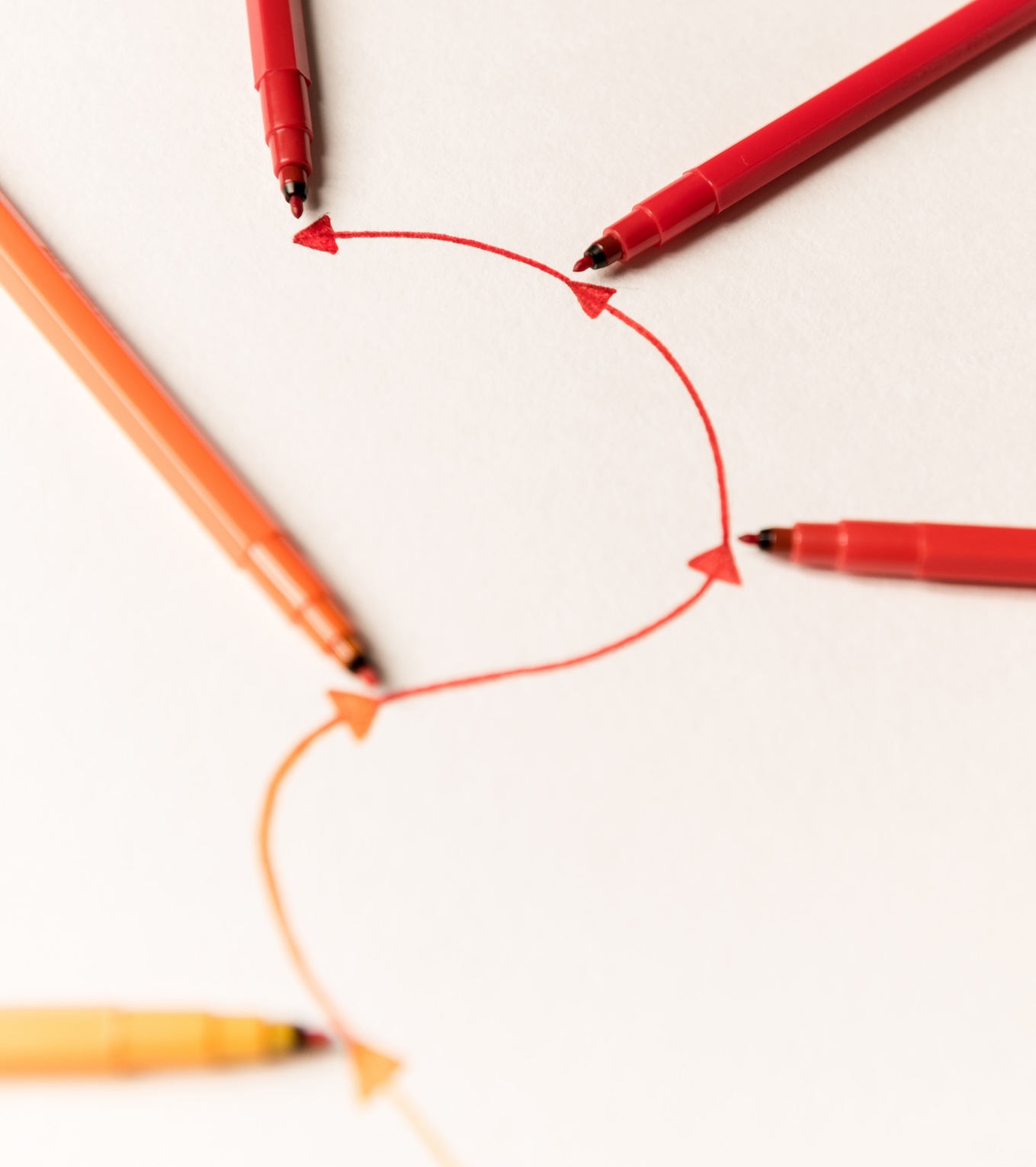 Rote und orangefarbene Stifte zeichnen eine kurvige Pfeillinie als Symbol für Storytelling im Gesundheitsmarketing beim Textquartier Marius von der Forst.